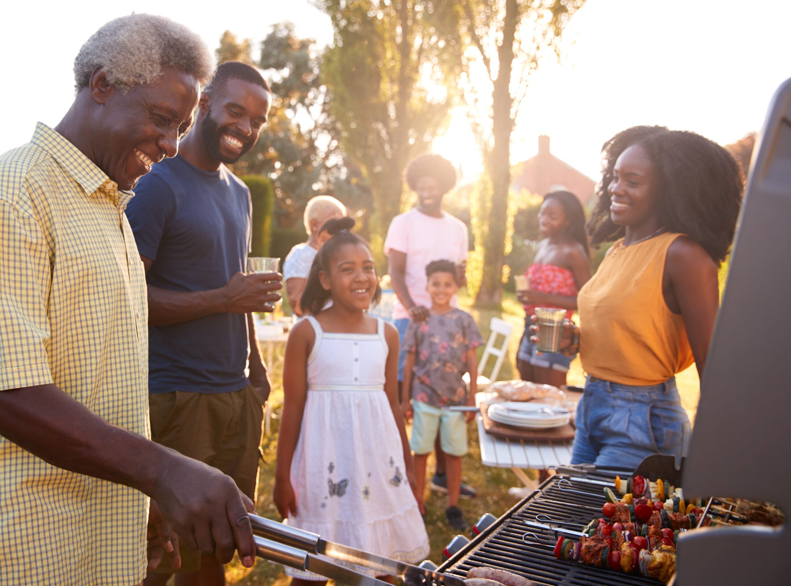 Multi generation  family barbecue, grandad grilling